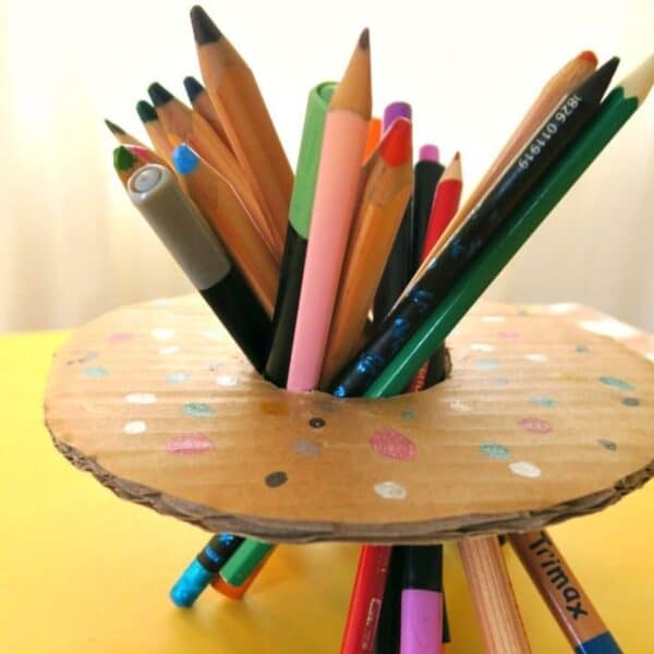 Bunch of pens and pencils in cardboard shaped as a donut.