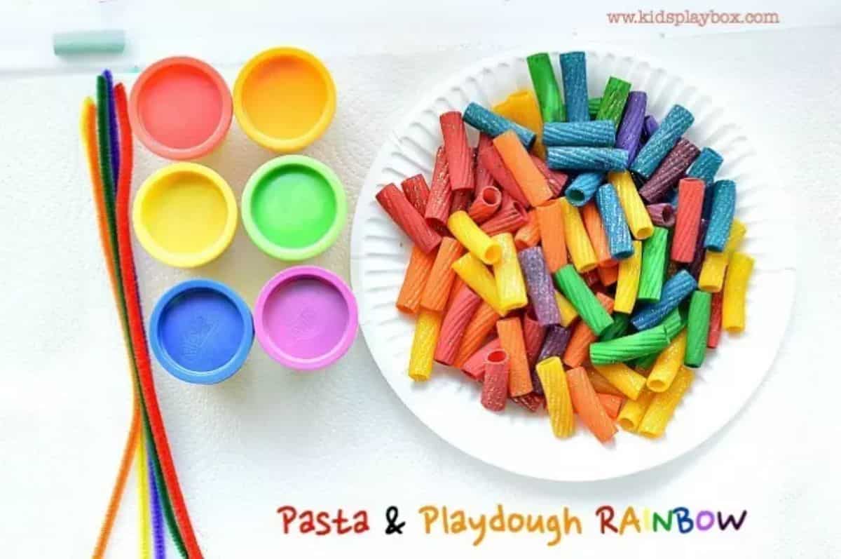 Plate of pasta and different colours of playdough on a table.