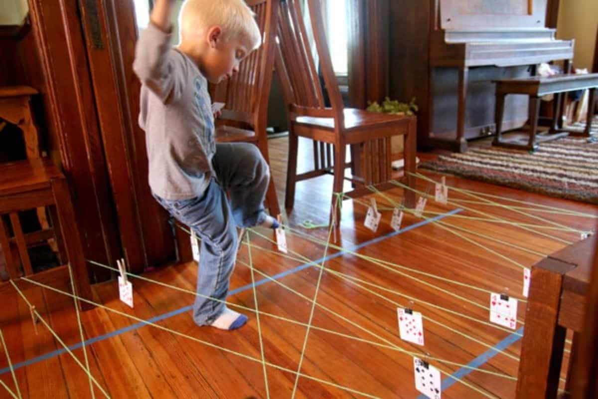 Young boy walking on string obstacle course at home.
