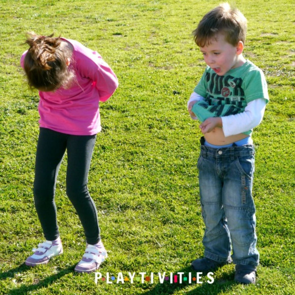 Boy in a green t-shirt and girl in a pink t-shirt playing outside.