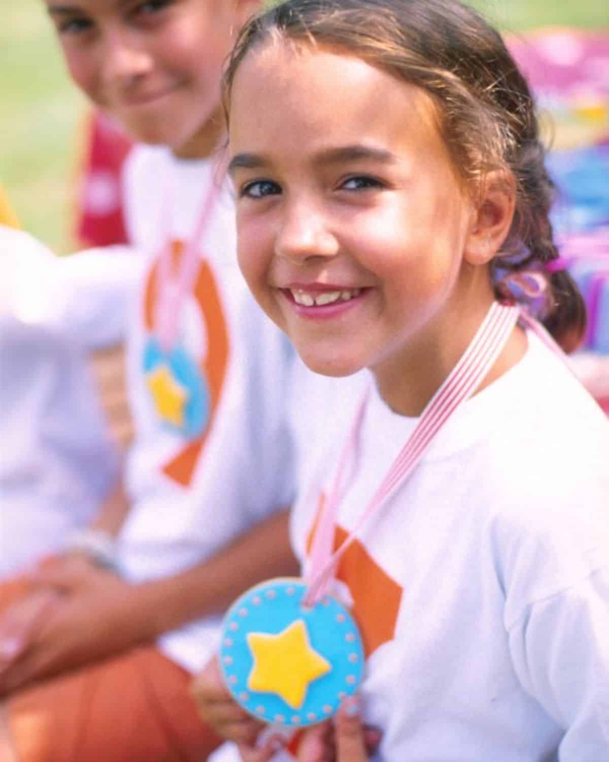 Young girl with a medal looking into a camera.