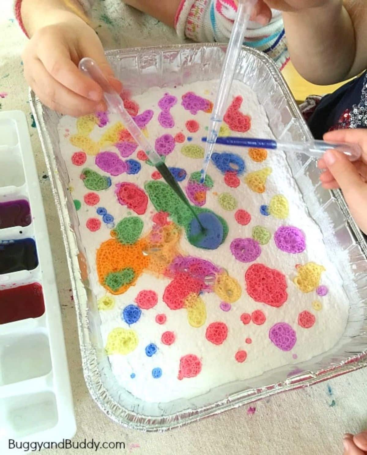 Hands are pouring colours from pippets to foil container.