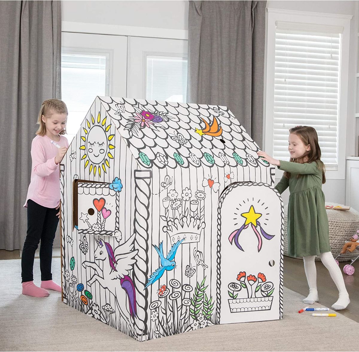 Two girls playing at unicorn cardboard house.