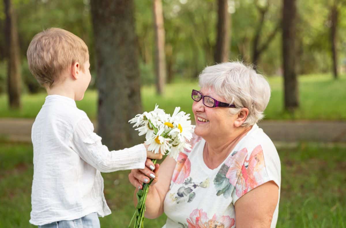 Young boy giving her grandmother a boquet of lowers.