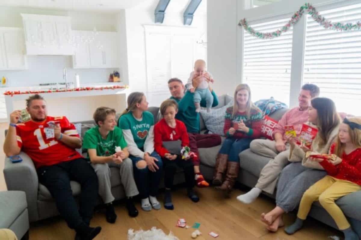 Whole family sitting on a sofa and playing a chritmas game.