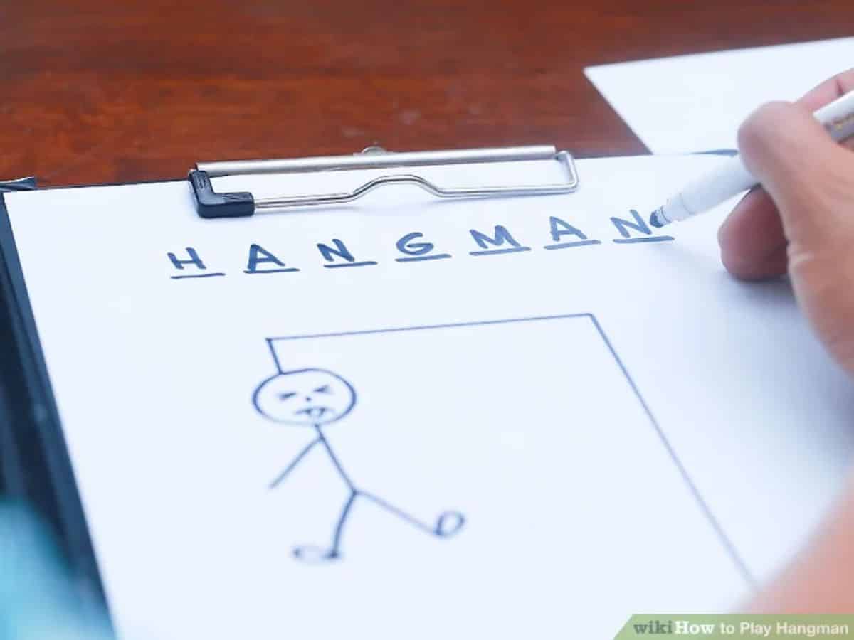 Hand holding a pen over a paper sheet with sigh - Hangman and drawning of a handman.