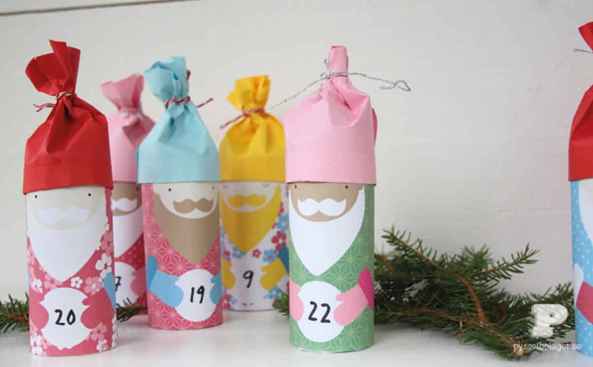 Advent calendar characters made from toilet paper rolls on a table with a tree branch.