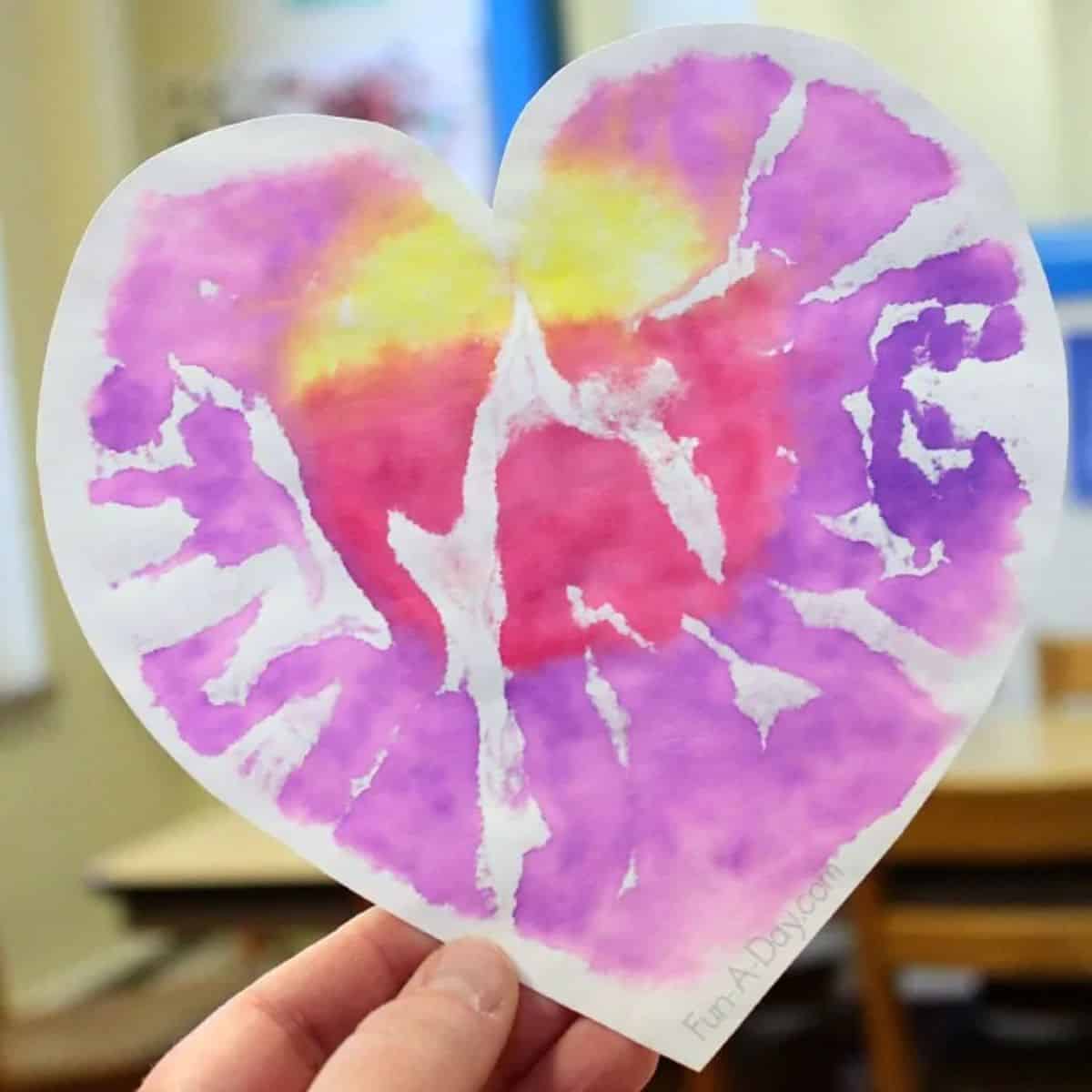 A hand holding Heart Print Valentine Art project.