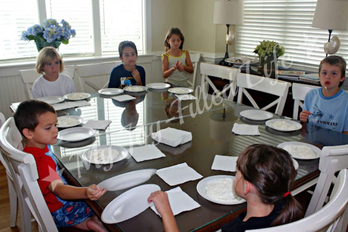 6 kids sitting at the table and playing Save THe KId  Party Game..