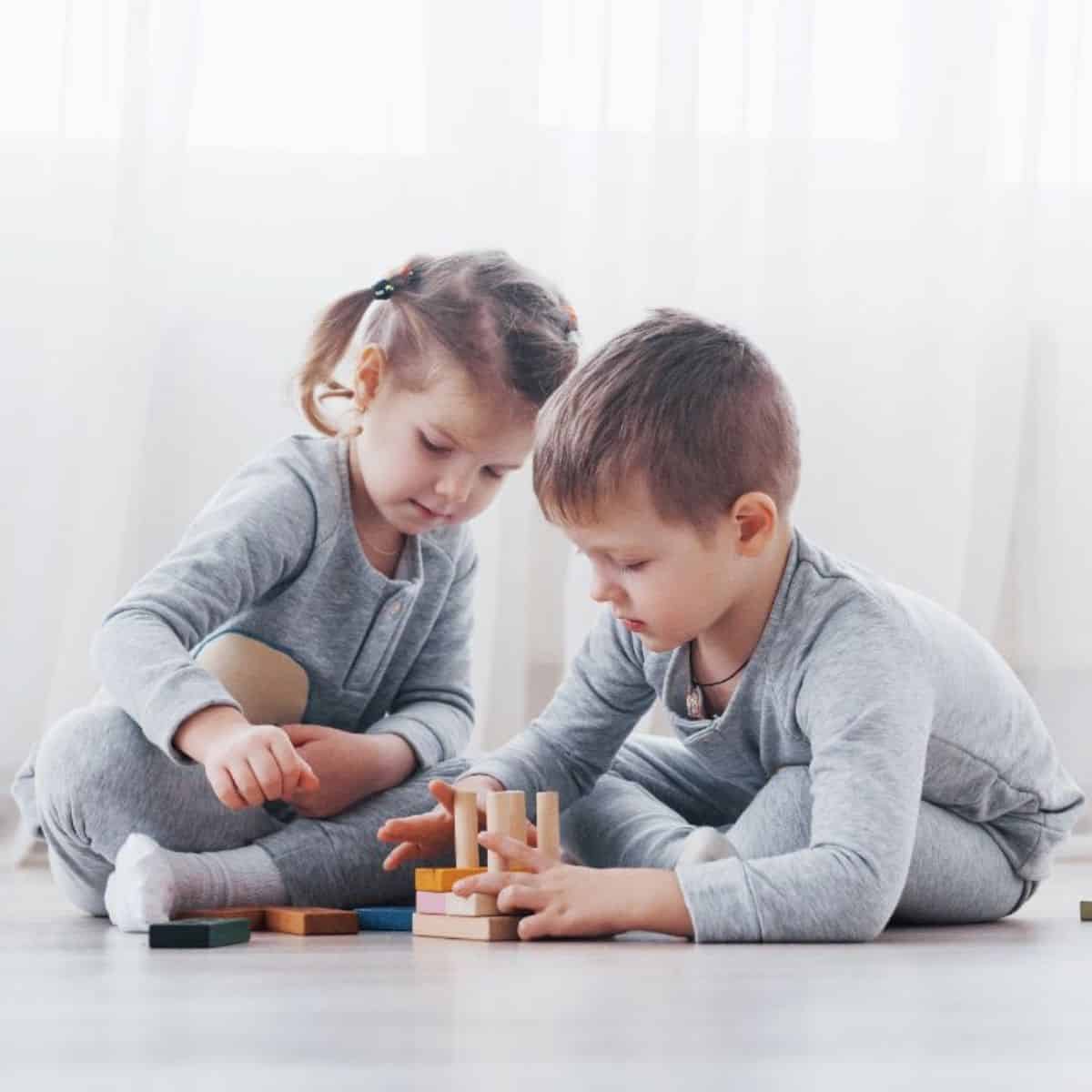 Two young kids playing together on the floor.