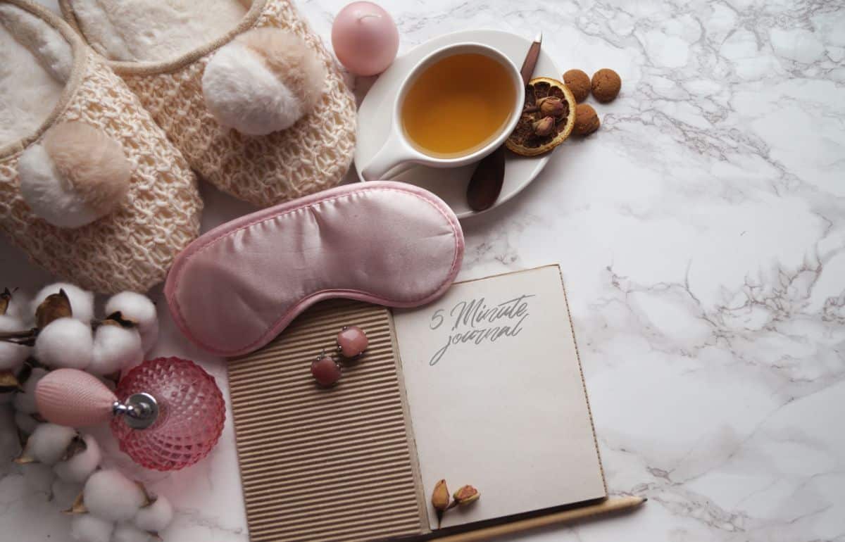 Bed routine concept- cup of tea, journal, sleep mask, parfume on a bed.