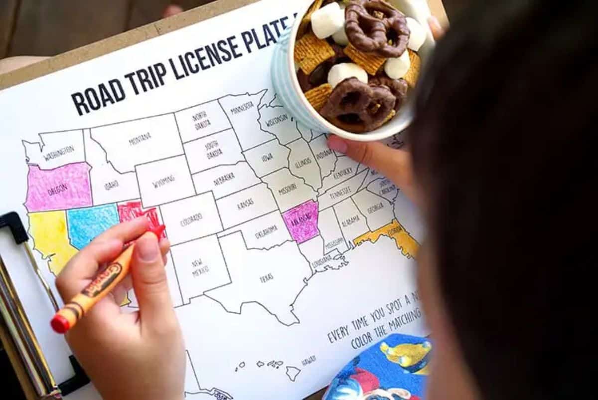 Kid with a pencil coloring a state on a map and holding bowl of sweets.