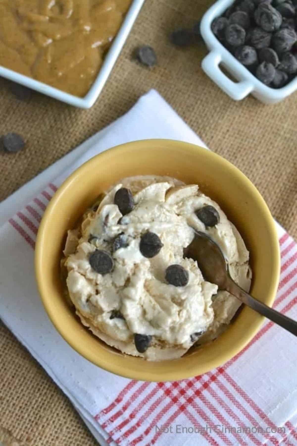 Bowl of reese's peanut butter cup frozen yogurt with a spoon on a table.