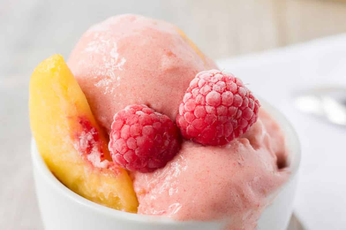 White bowl of raspberry-peach ice cream.