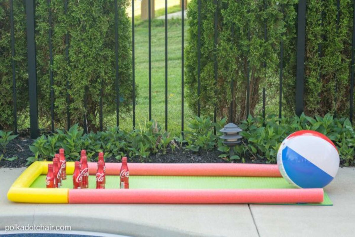 Pool ball, coke bottles, pool noodles on a concrete pavement.