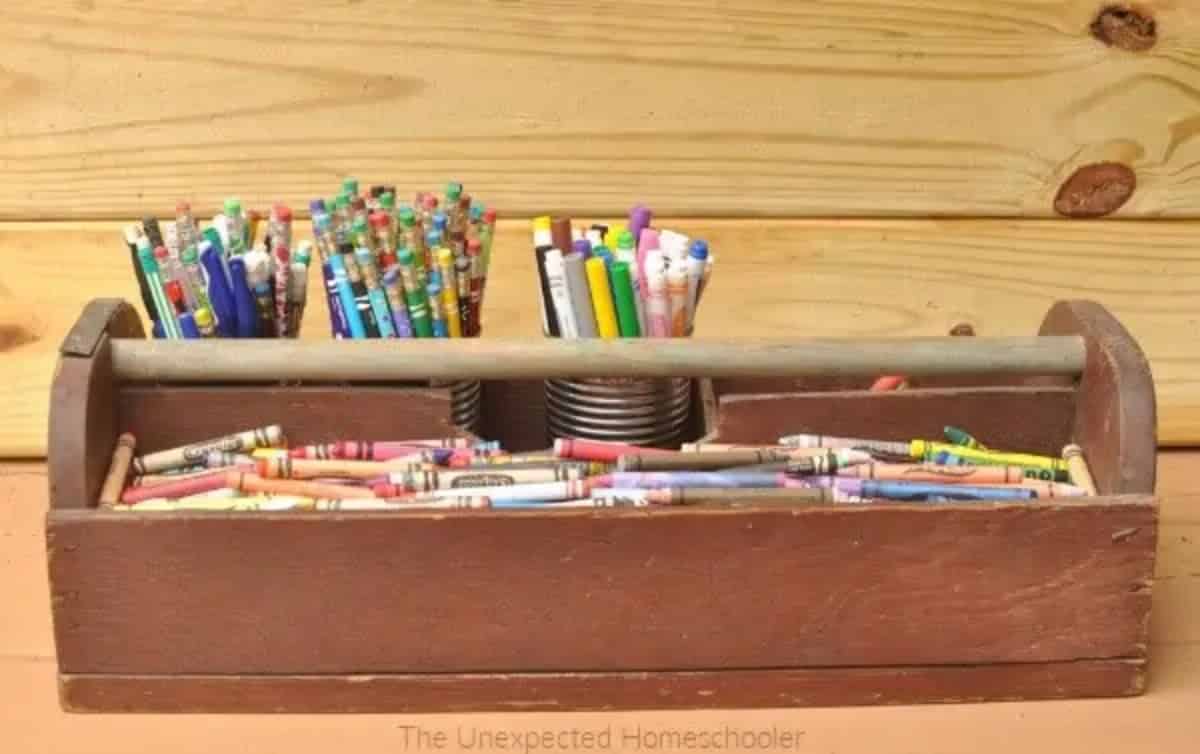 Bunch of pencils, pens and wax pencils in a wooden and a metal container.