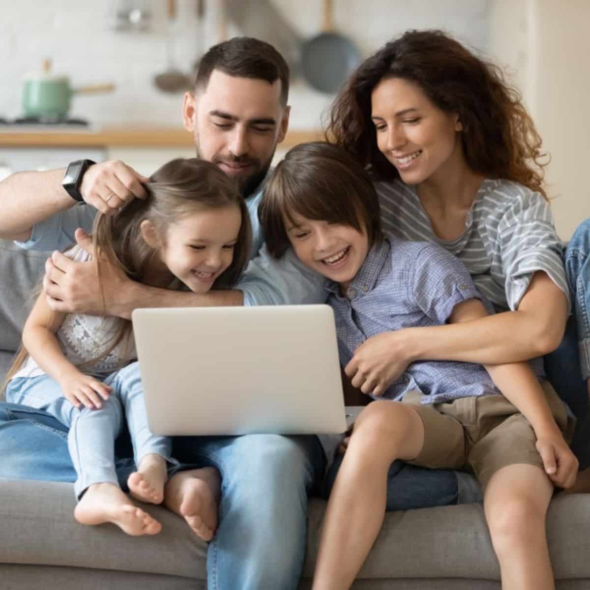Image of young family sitting on a sofa and watching laptop.