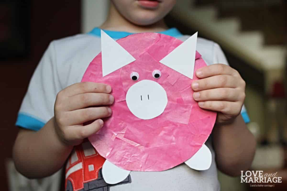 Kid holding a peppa pig paper craft in hands.
