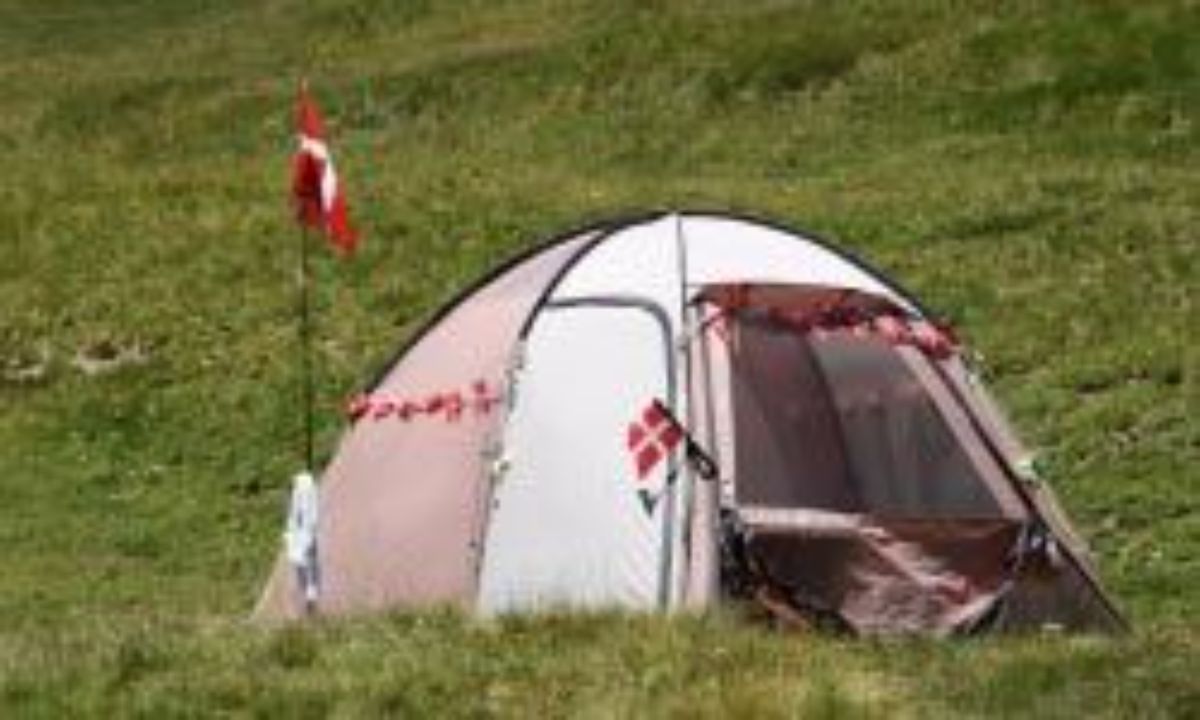 a domed canvas tent is erected on the grass, a red flag is on the top