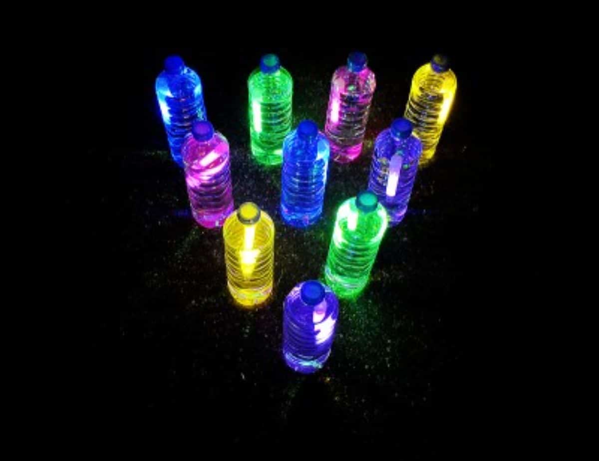 10 water bottles glowing in the dark arranged in a bowling triangle