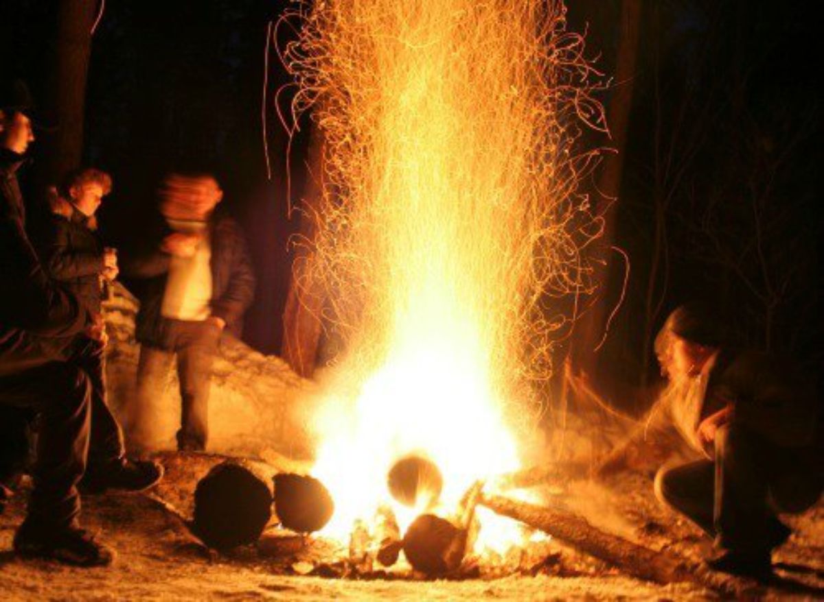 a blurred image of a group sitting around a roaring campfire