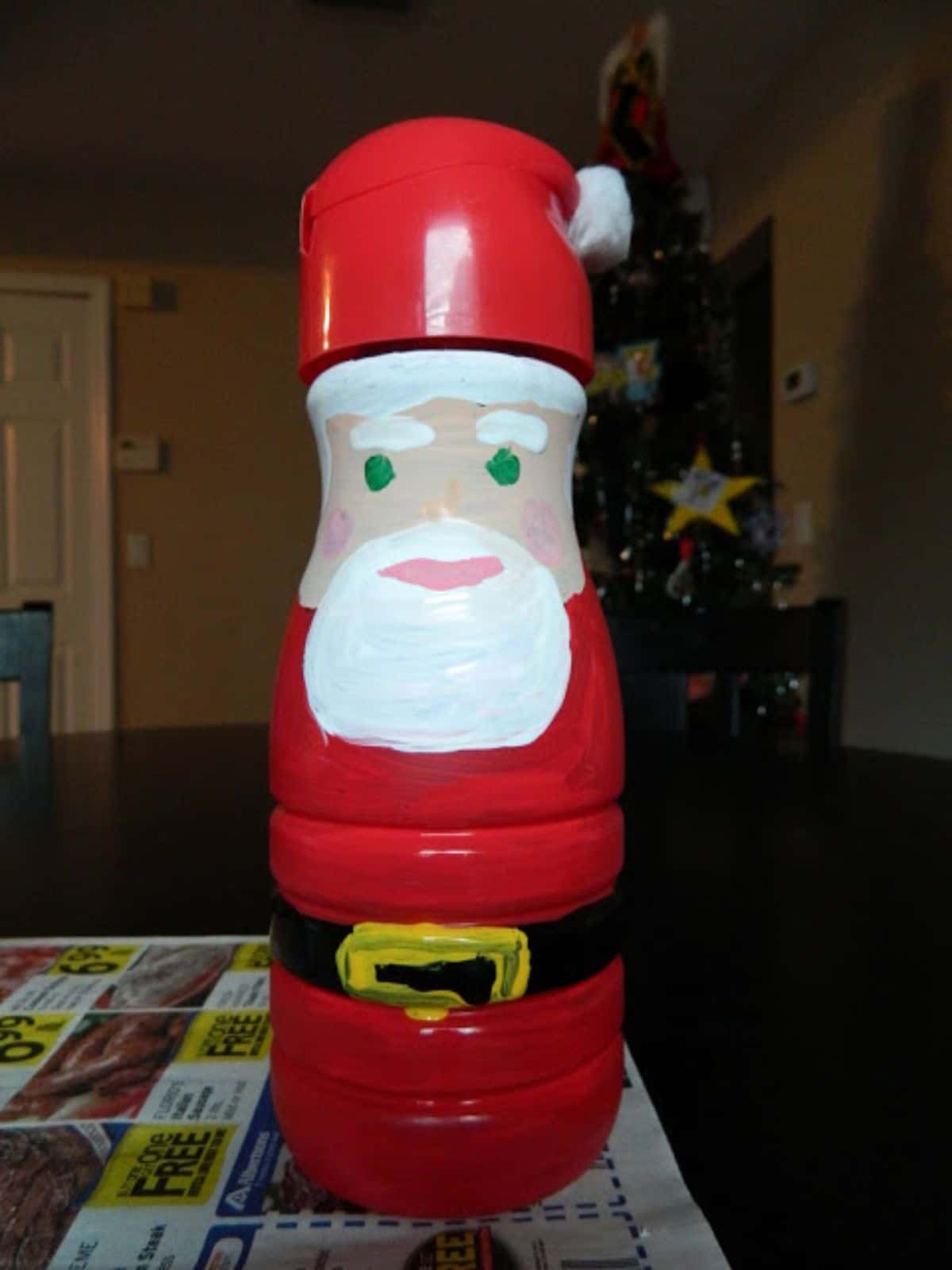 on a piece of newspaper is a creamer bottle painted to look like santa