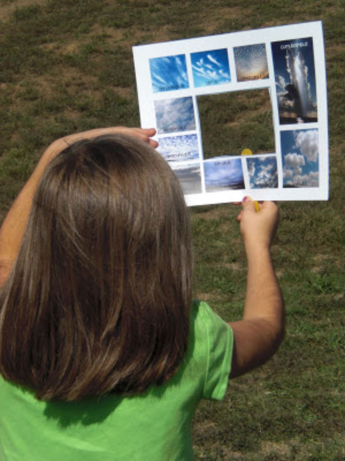 a child in a green shirt holds up a card with photos of clouds on it