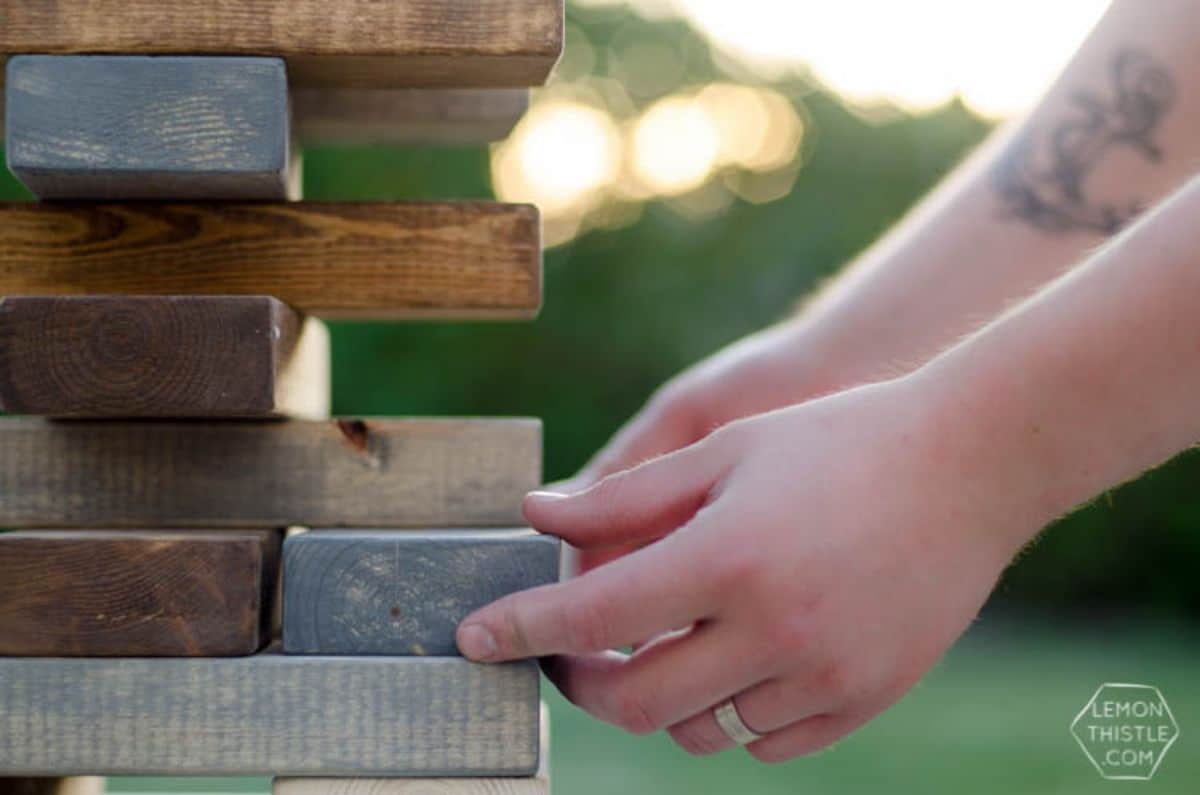 hands can be seen holding one block of a giant jenga game