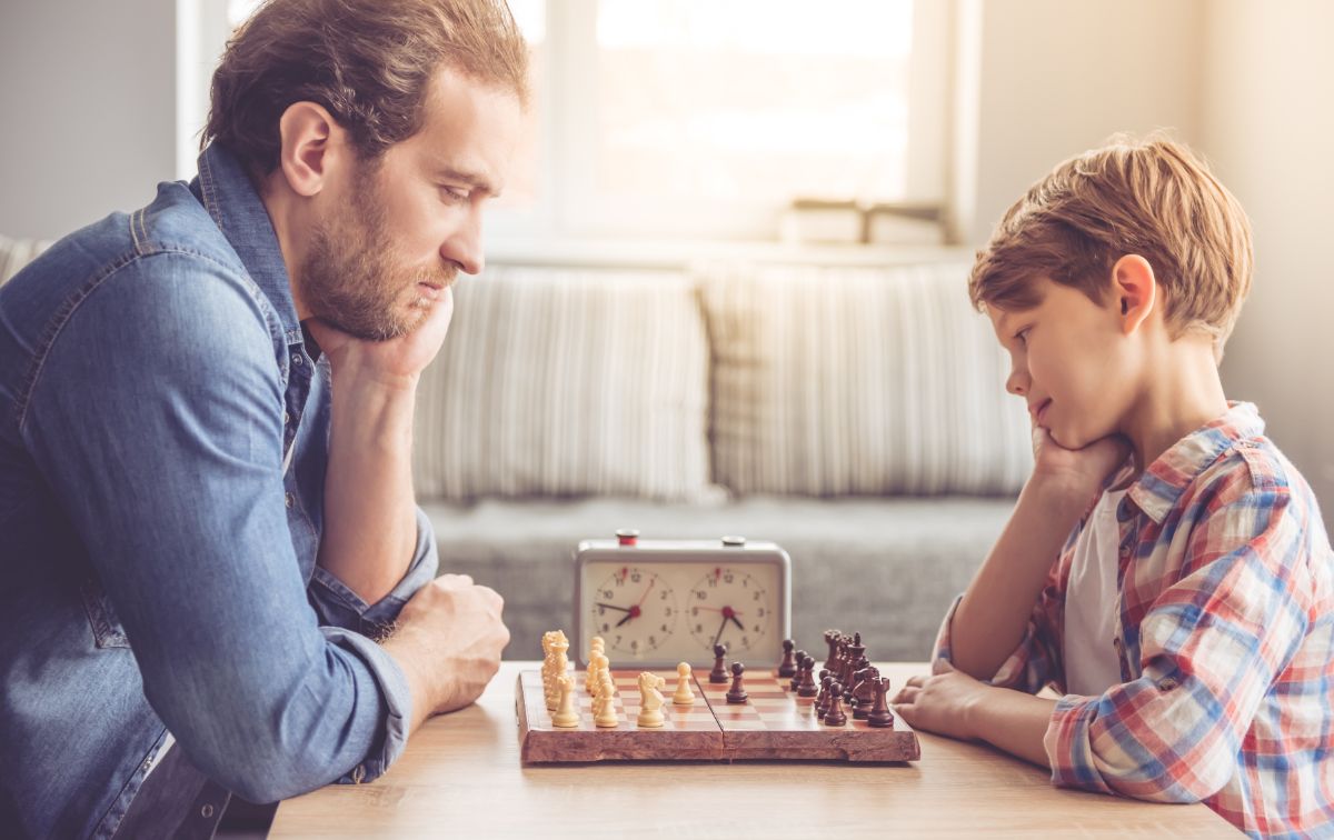 a father and son sit at a low table playing chess