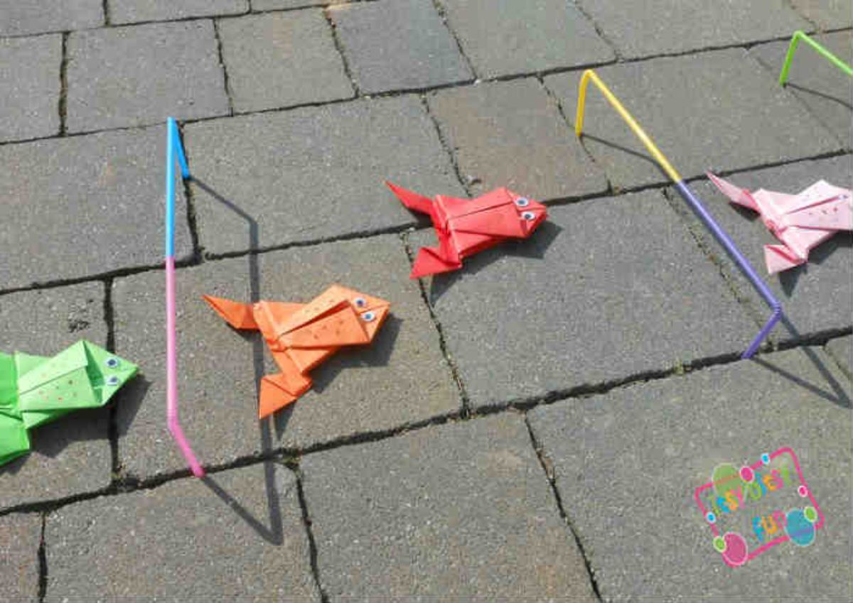 colored origami frogs are laid out on a stone floor, hurdles made of plastic straws are also seen