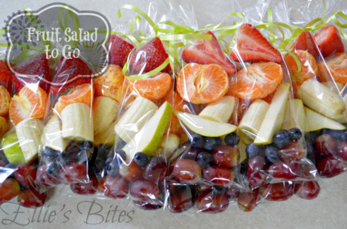 The text reads " Fruit Salad to go" The image is of bags of fruit salad containing red grapes, blueberries, apple slices, mandarin slices and strawberries