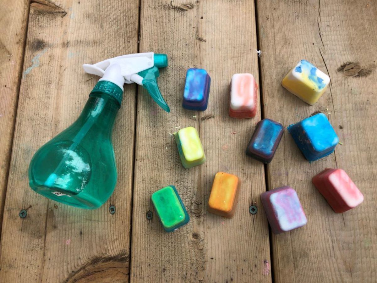 on a wooden table is a spray bottle with different colored ice cubes next to it