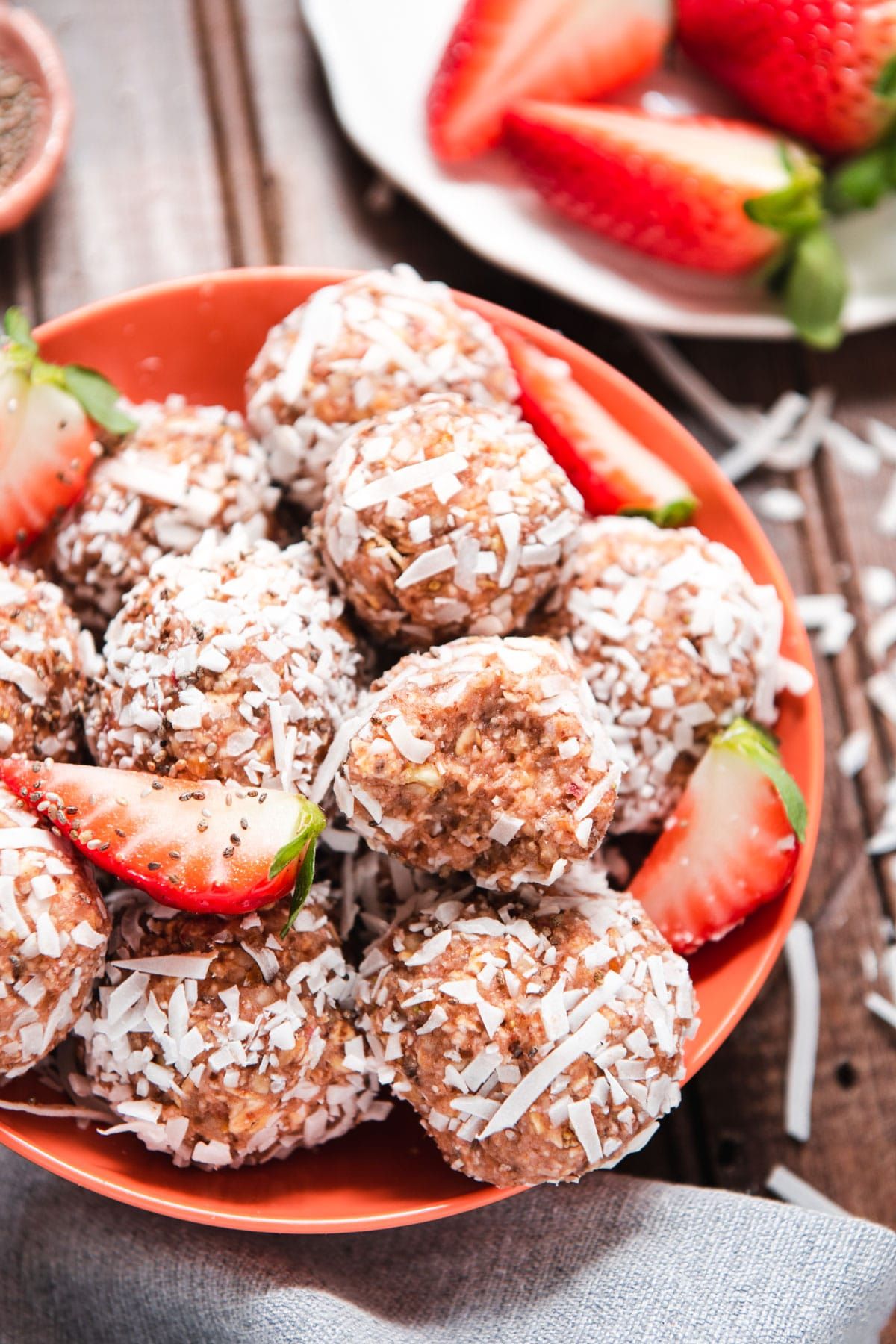 a red bowl of strawberry almond balls rolled in dessicated coconut