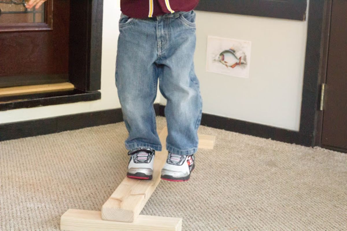 a close up shot of a boy in jeans standing on a wooden beam