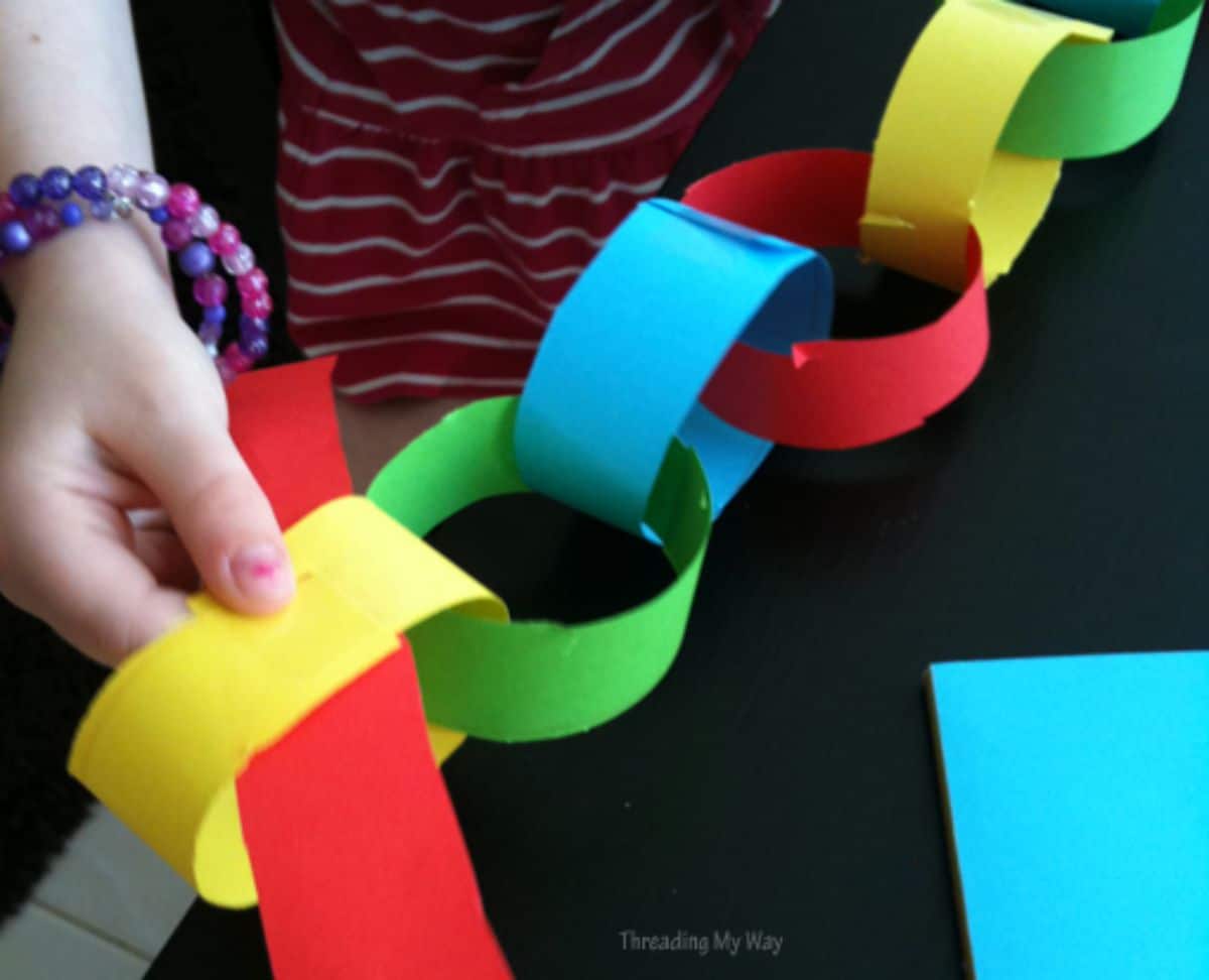 A hand holds the end of a colored paper chain