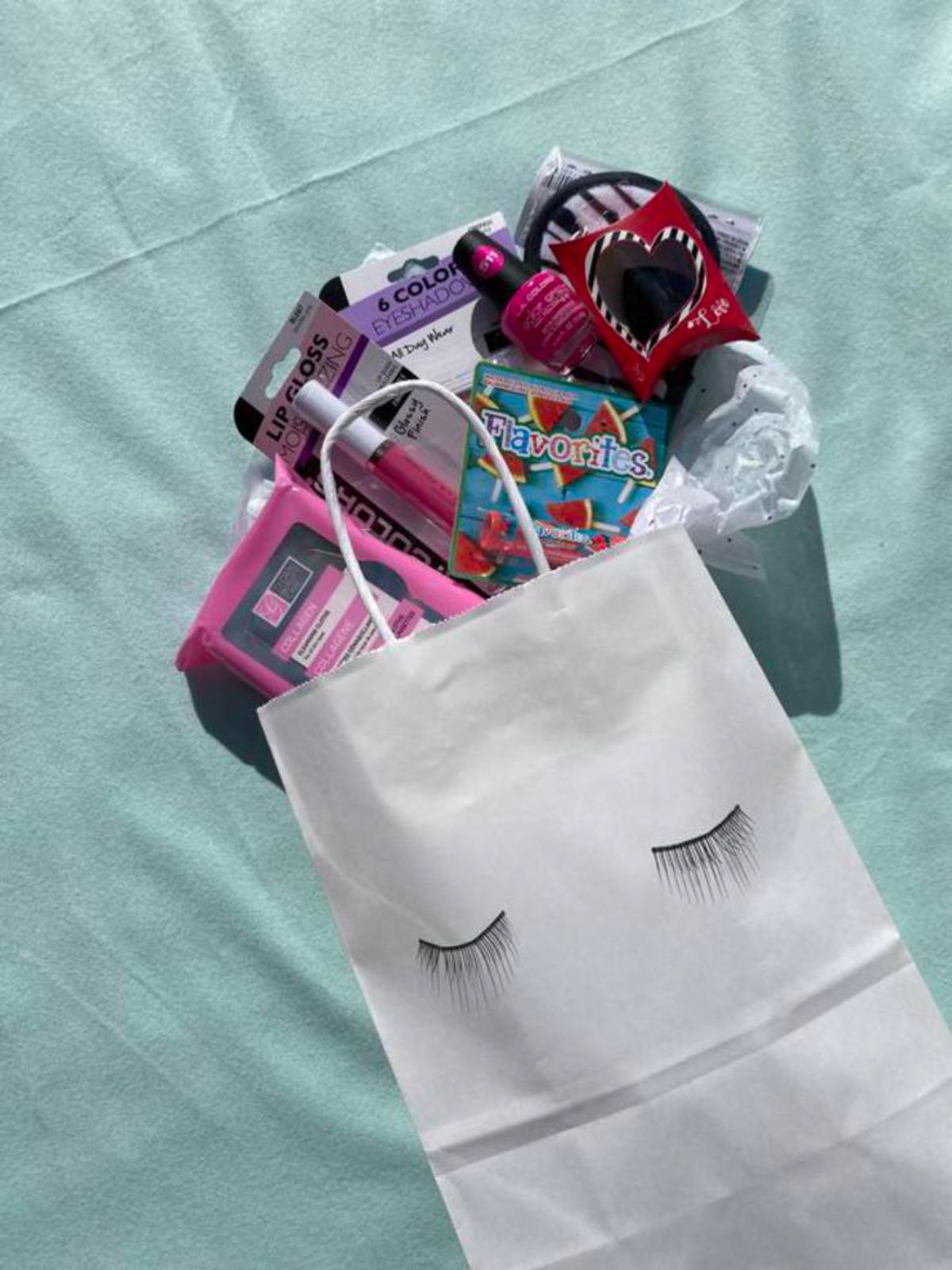 a white bag with eyelashes on the front with various makeup and beuaty items peeking over the top