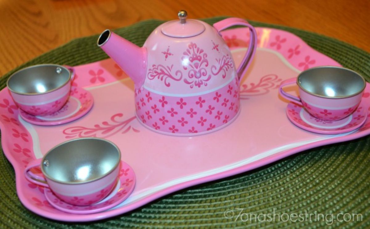a pink tin tray holds 3 pink cups and saucers, and a pink teapot