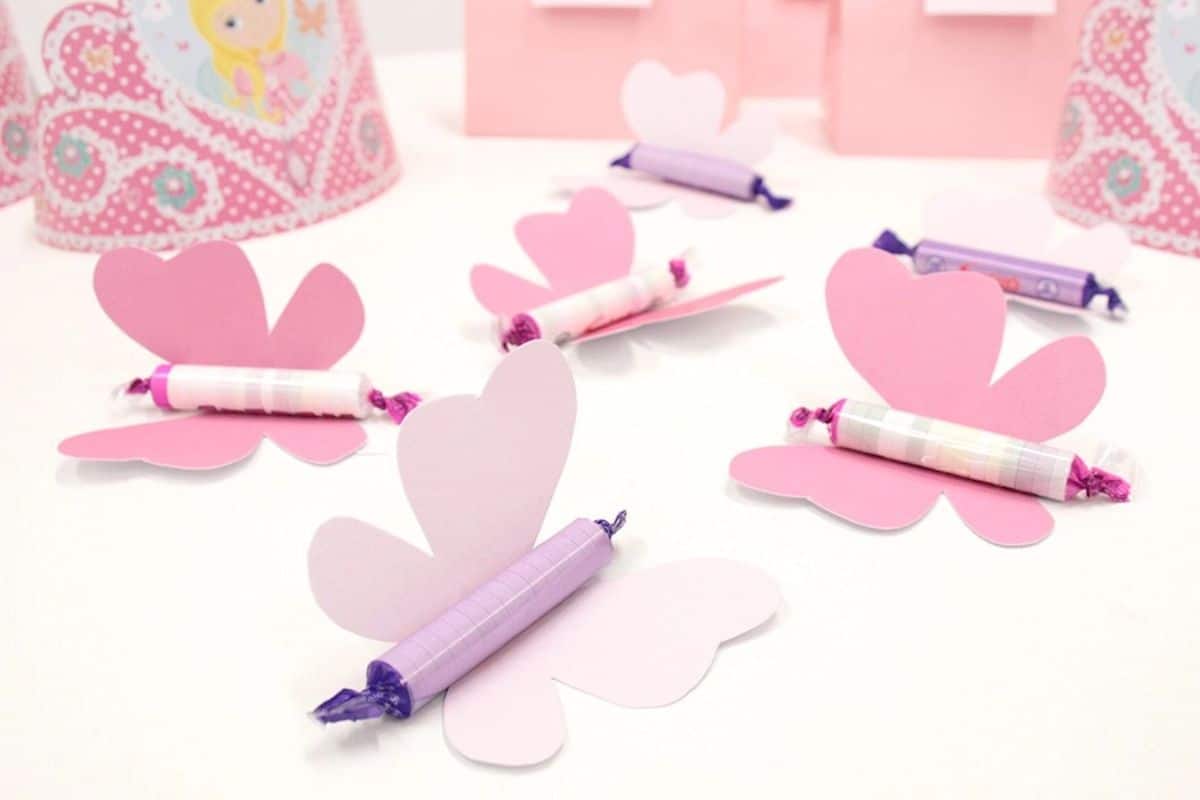 6 paper butterflies with tubes of sweets attached sit on a table