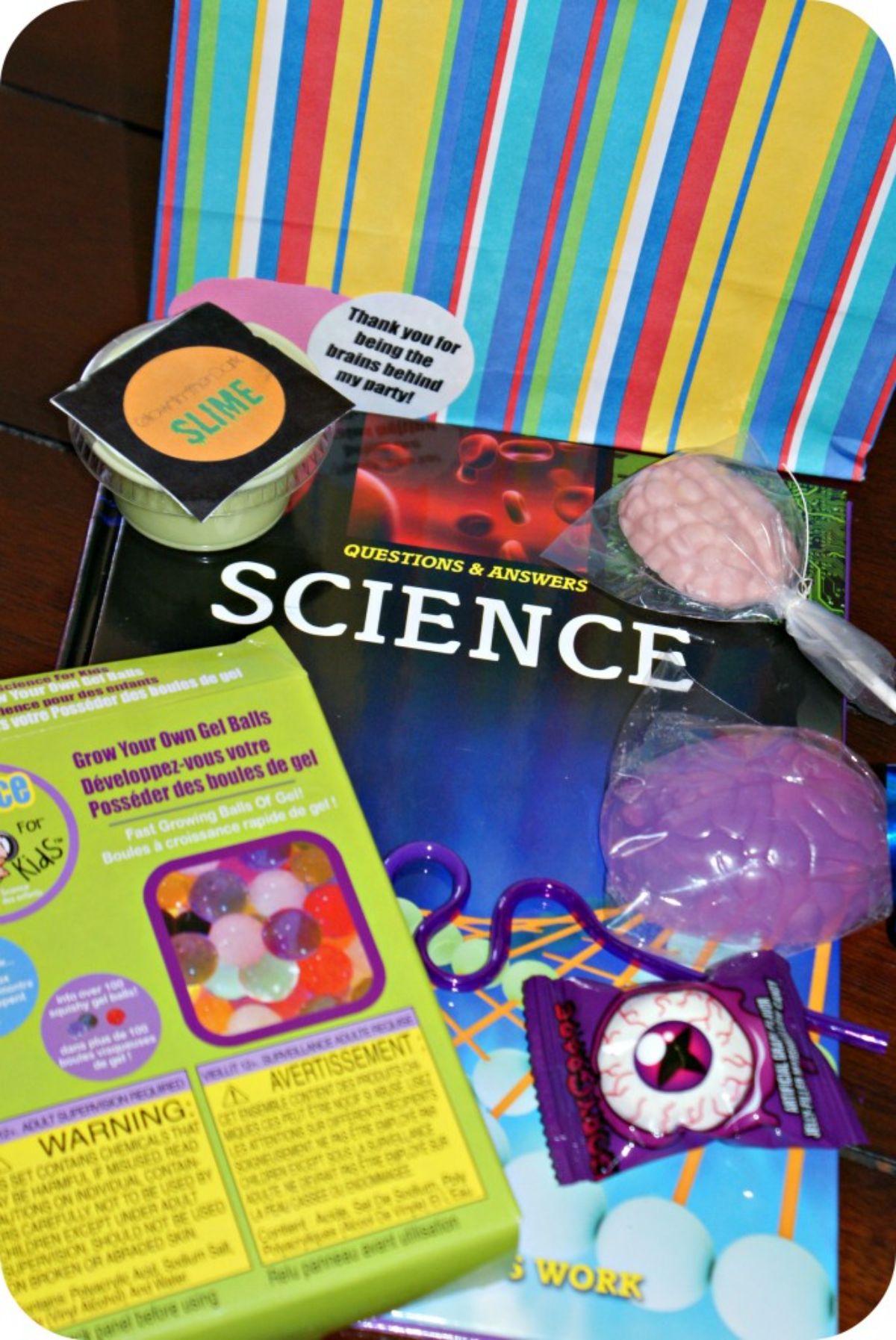 a striped paper bag sits on the table, In front is a selection of science-themes items