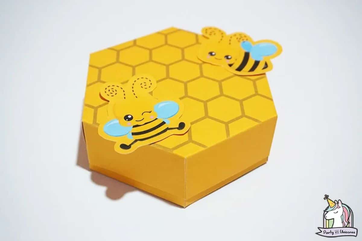 a hexagonal paper box designed to look like a beehive with 2 paper bees on top