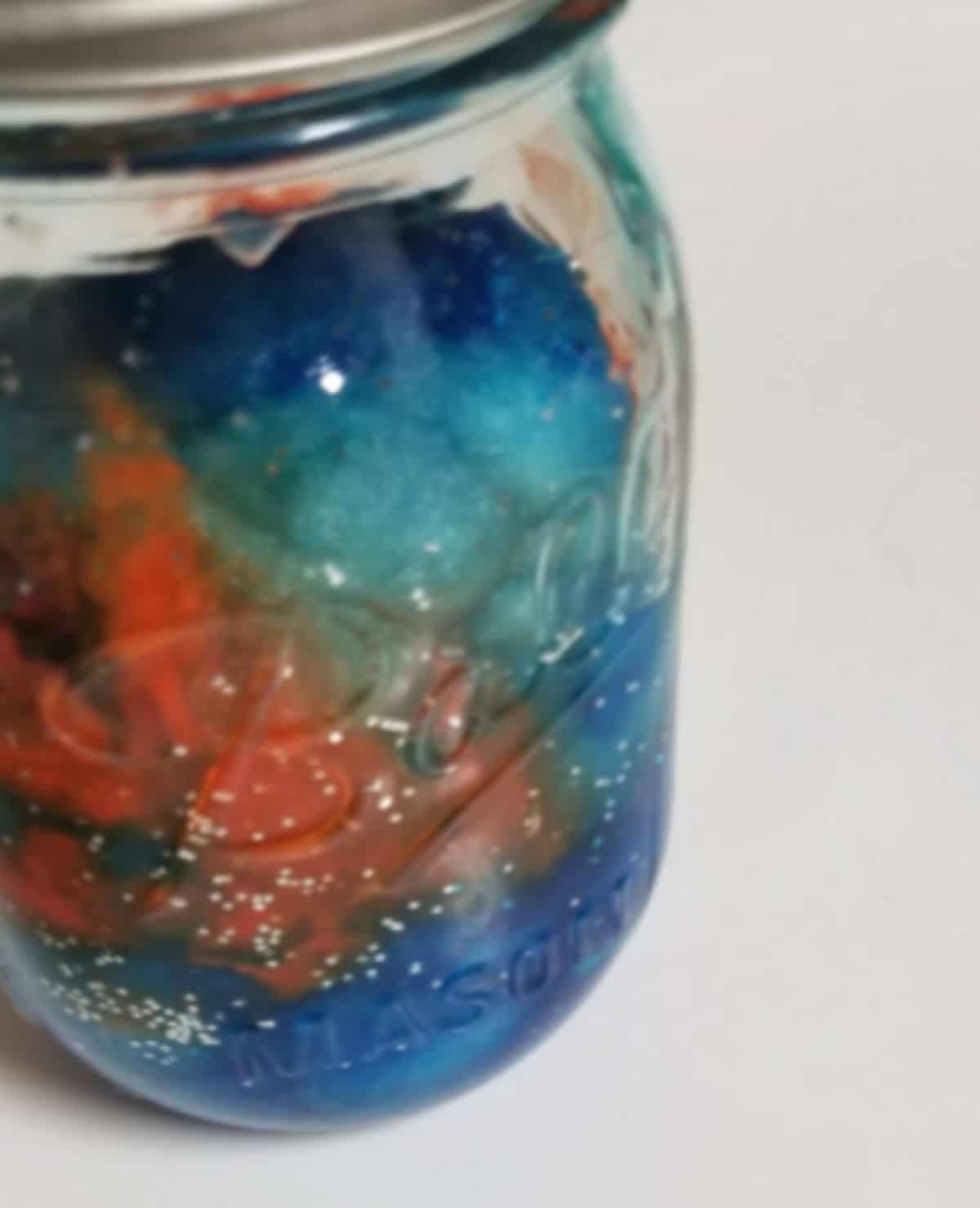 a jar full of a mix of colors and liquid
