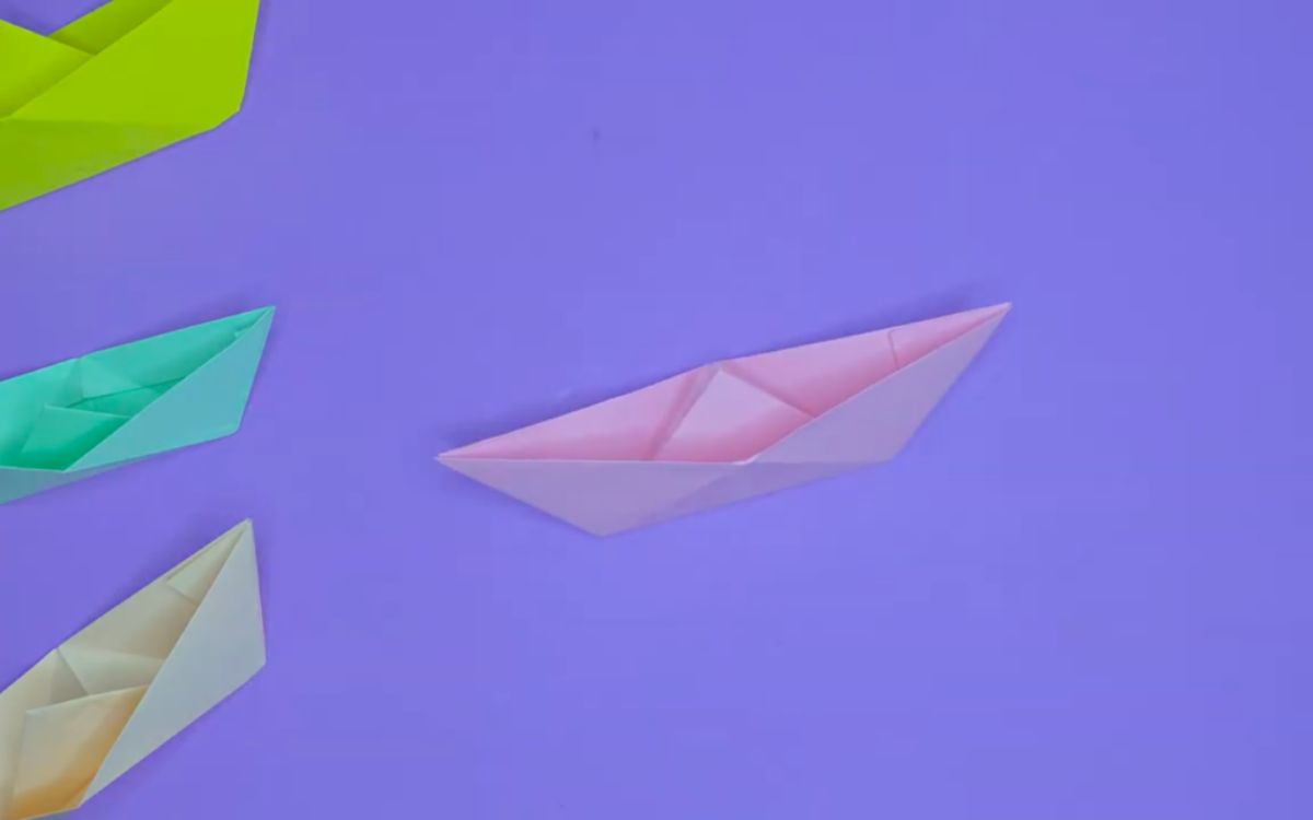 4 colored paper origami boats on a purple background