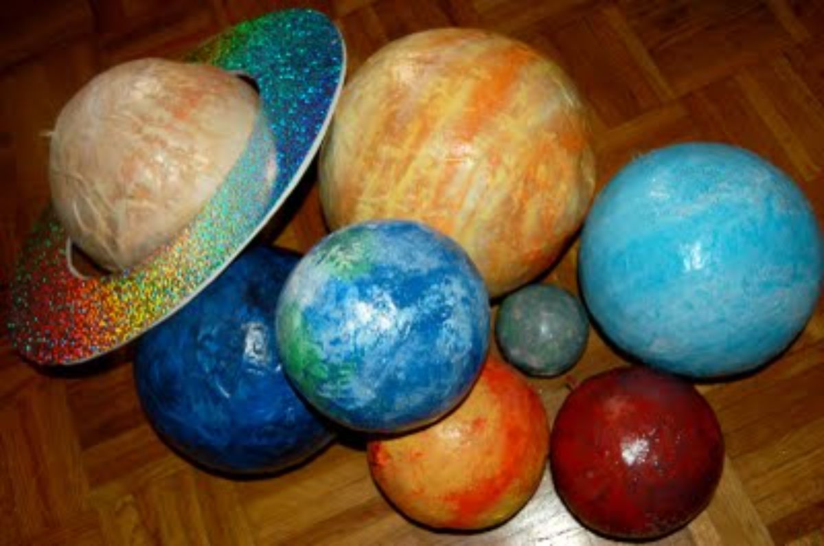 a pile of paper mache planets sit on a parquet floor