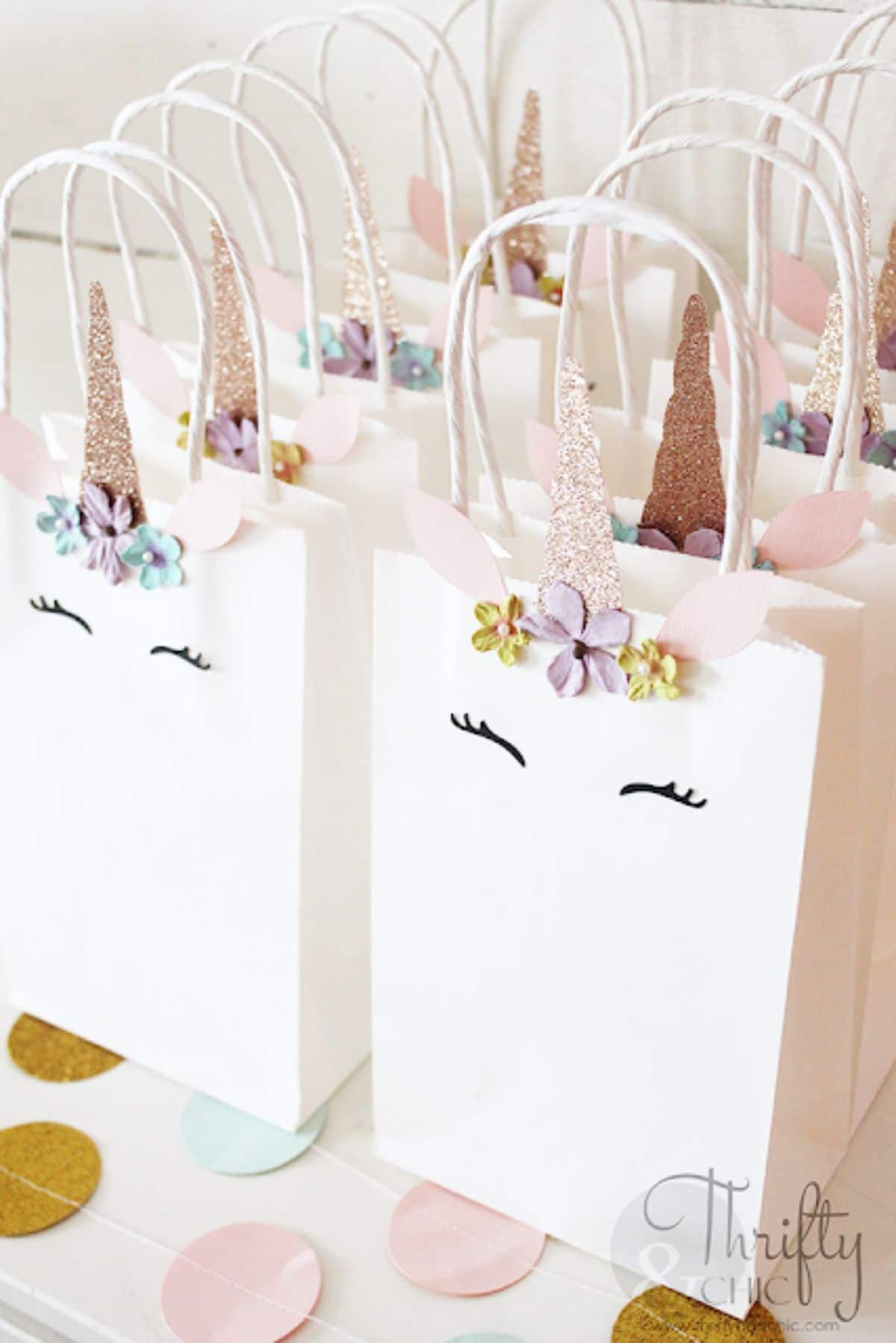 8 lined up white paper bags with unicorn designs on them