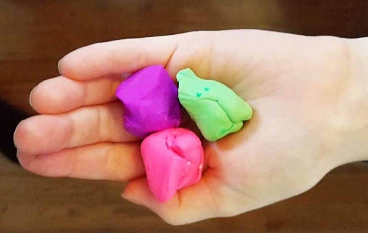 a hand holds 3 squares made of different colored clay