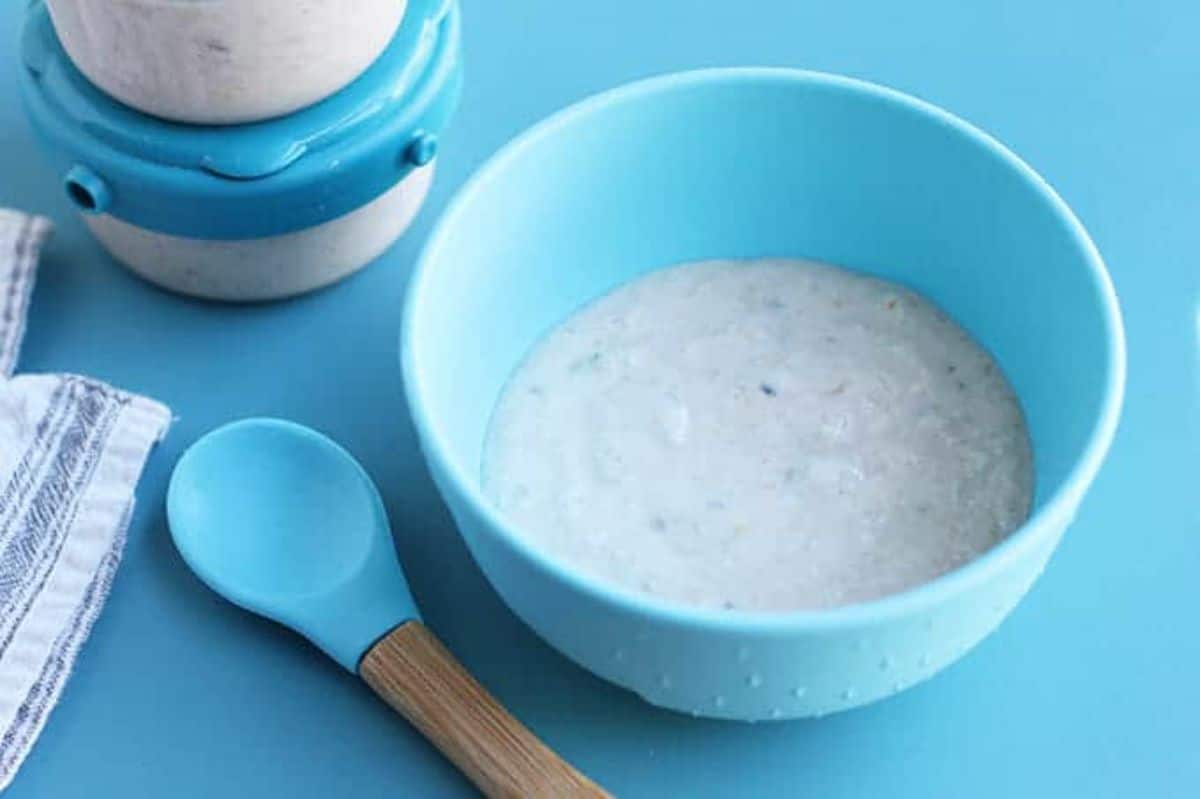 a blue bowl contains oatmeal. A silicone topped spoon is next to it