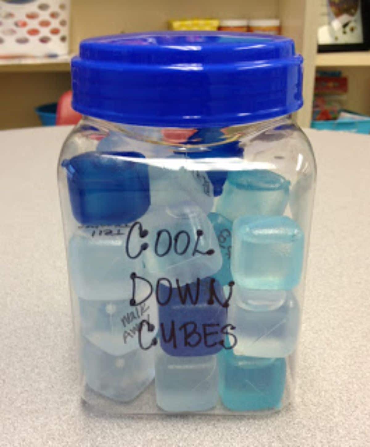 a plastic jar is filled with reusable ice cubes that all have writing on them. The jar is labelled "cool down cubes"
