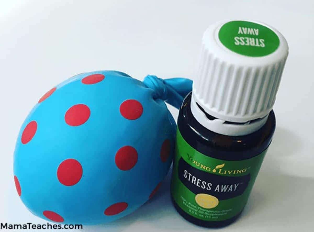 a blue and red spotted stress ball sits next to a bottle of stress away essential oils
