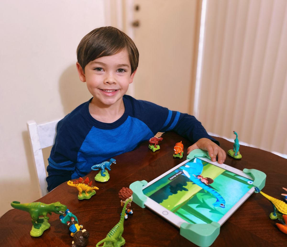 boy in blue shirt at brown table with dino game