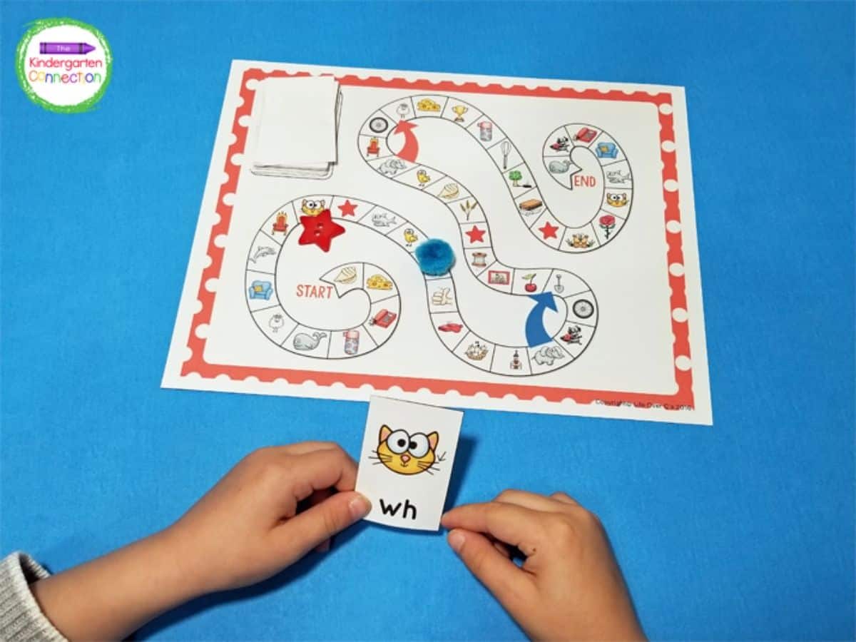 Kid's hand holding a digraph board game card.